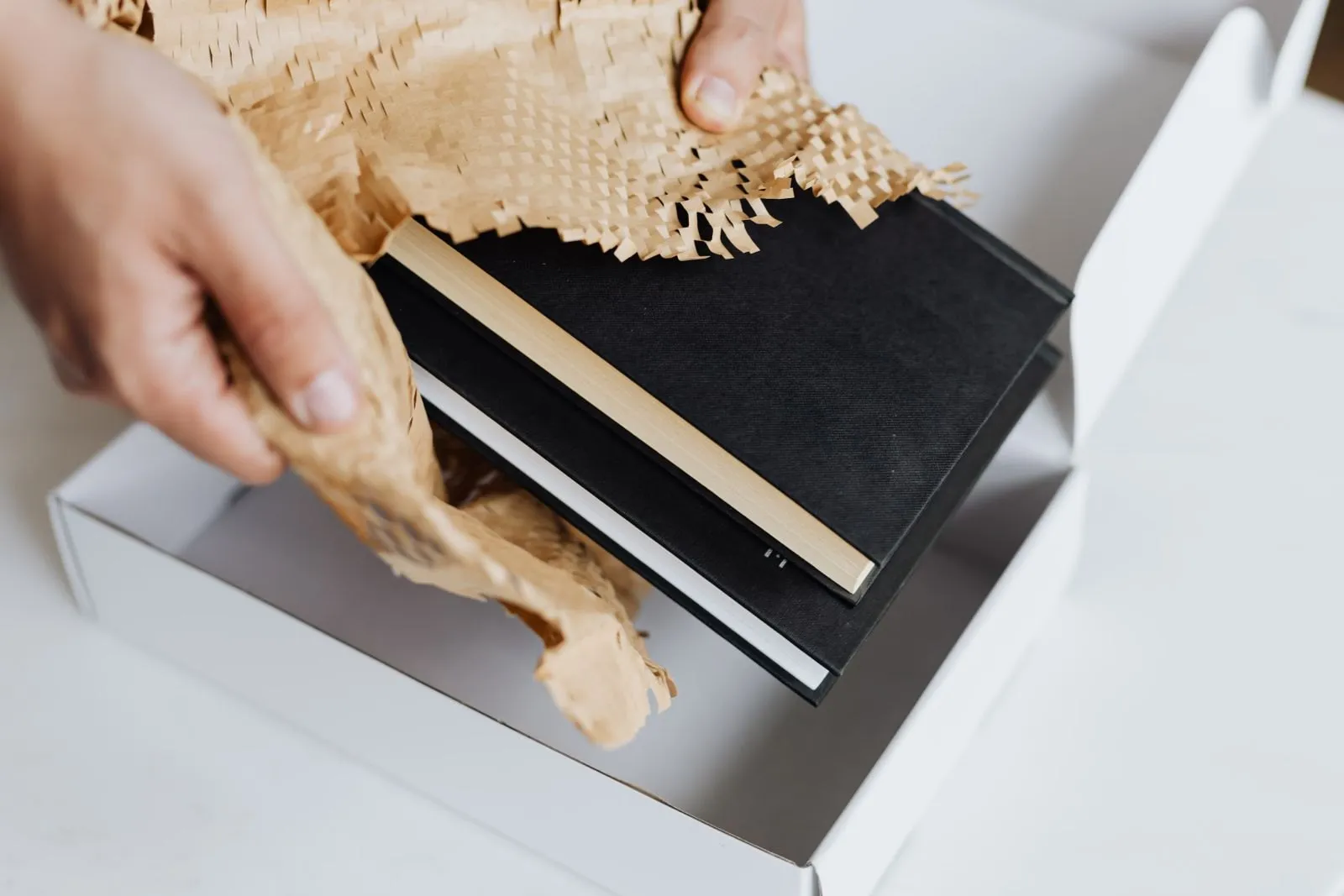 Two wrapped notebooks placed into an open gift box